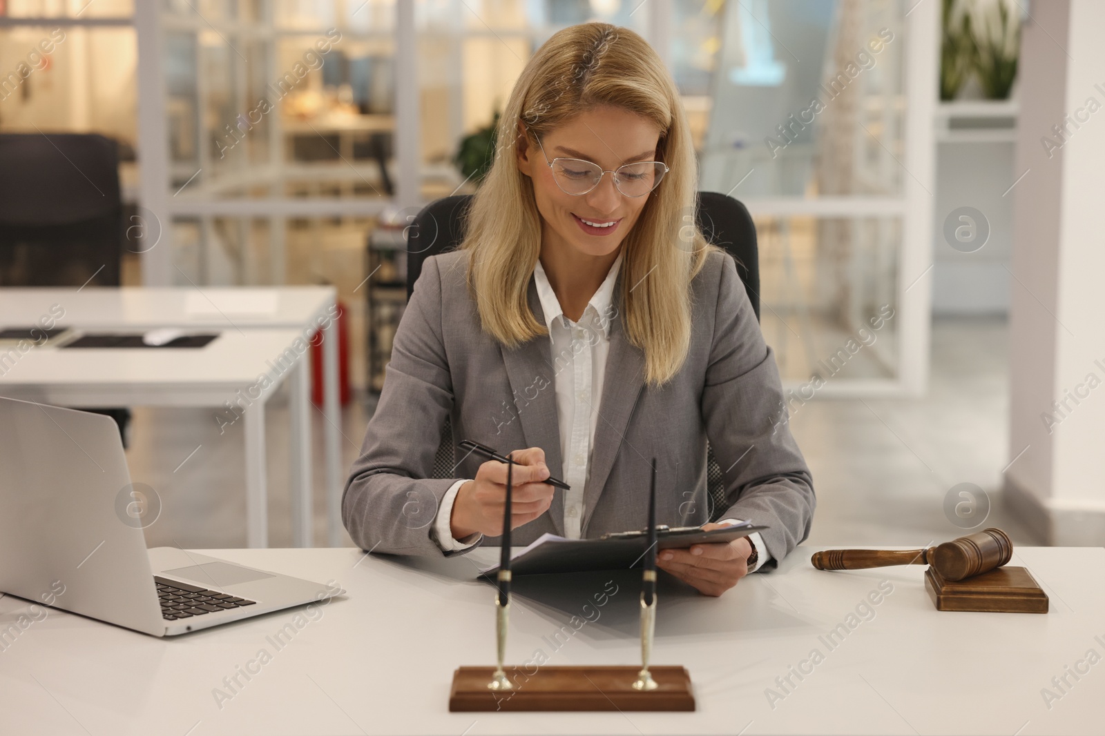 Photo of Smiling lawyer with clipboard working at table in office