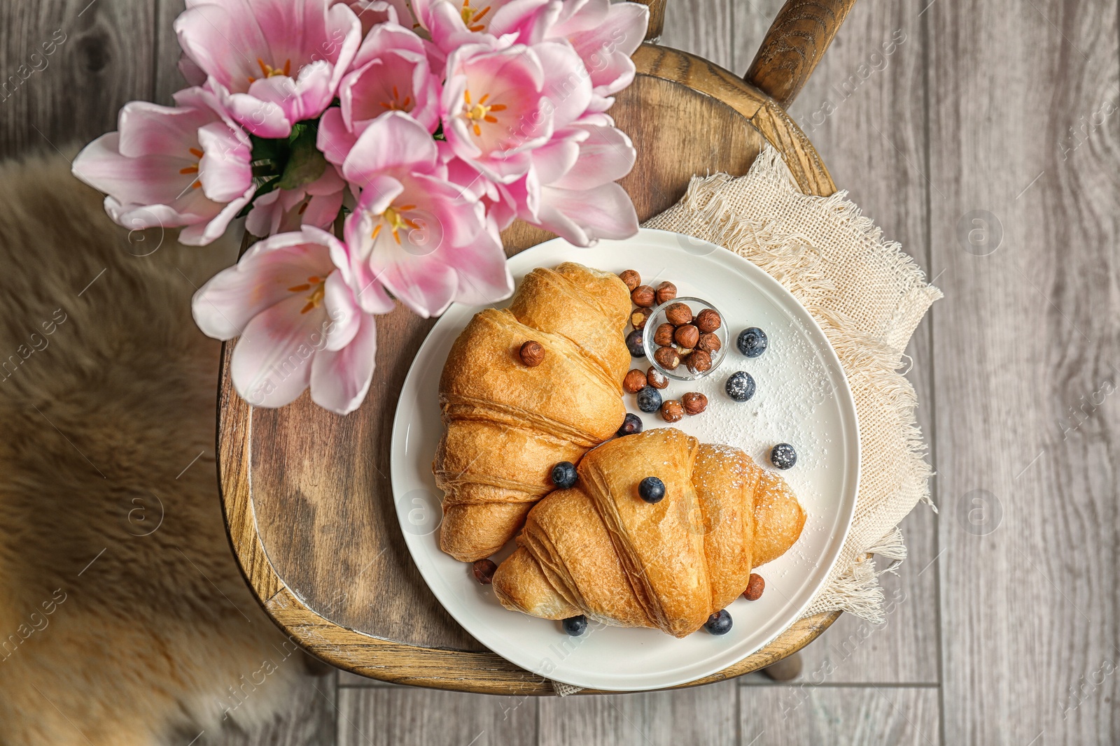 Photo of Plate with tasty croissants on chair, top view