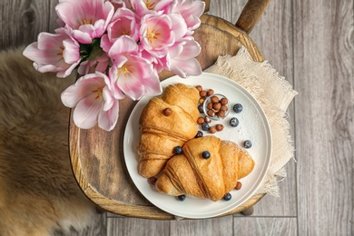 Photo of Plate with tasty croissants on chair, top view