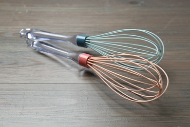 Photo of Two whisks on wooden table, closeup. Kitchen tool