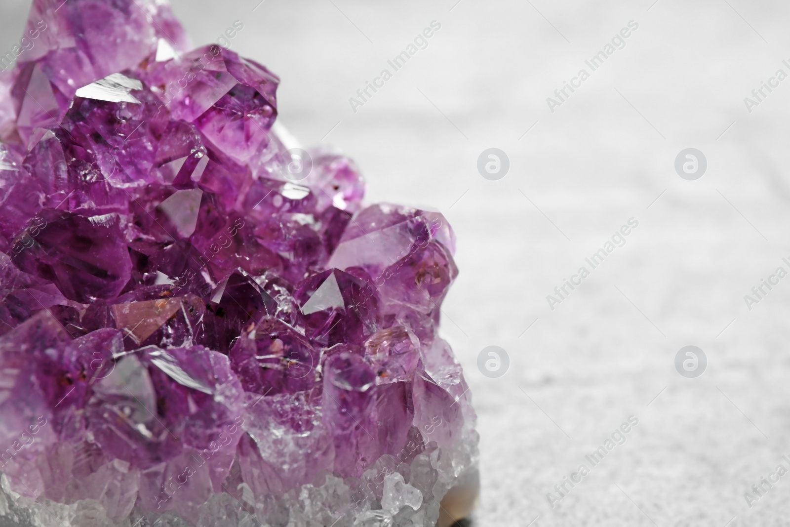 Photo of Beautiful purple amethyst gemstone on grey table, closeup view. Space for text