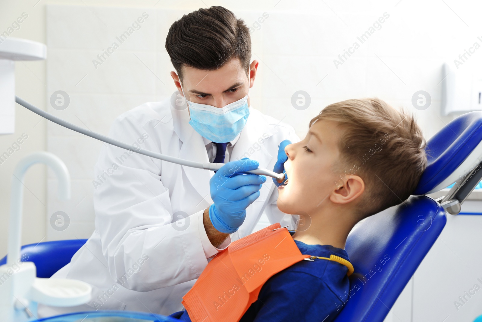 Photo of Professional dentist working with little boy in clinic