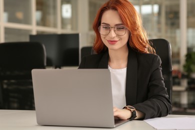 Photo of Woman working with laptop at white desk in office