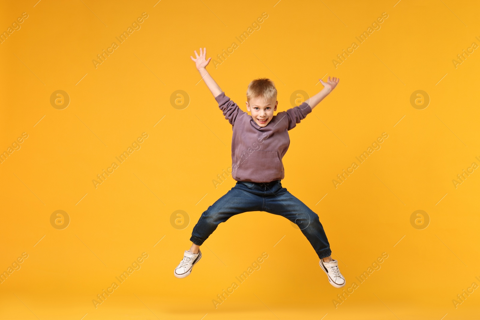 Photo of Happy little boy dancing on yellow background