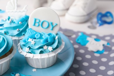 Photo of Delicious cupcakes with light blue cream and toppers for baby shower on table, closeup