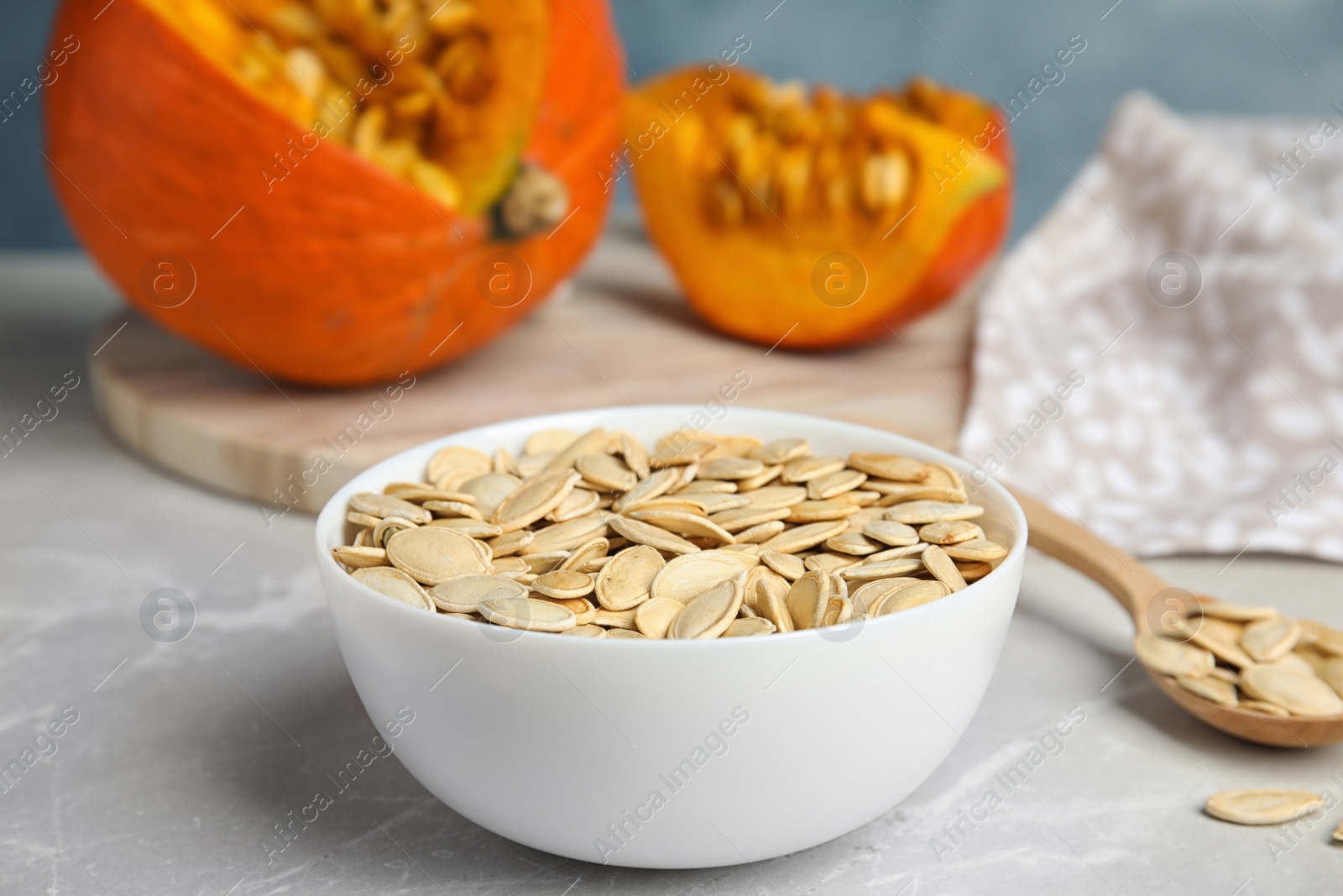 Photo of Bowl of raw pumpkin seeds on light grey marble table