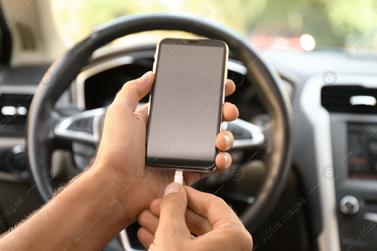 Photo of Man connecting charging cable to smartphone in car, closeup