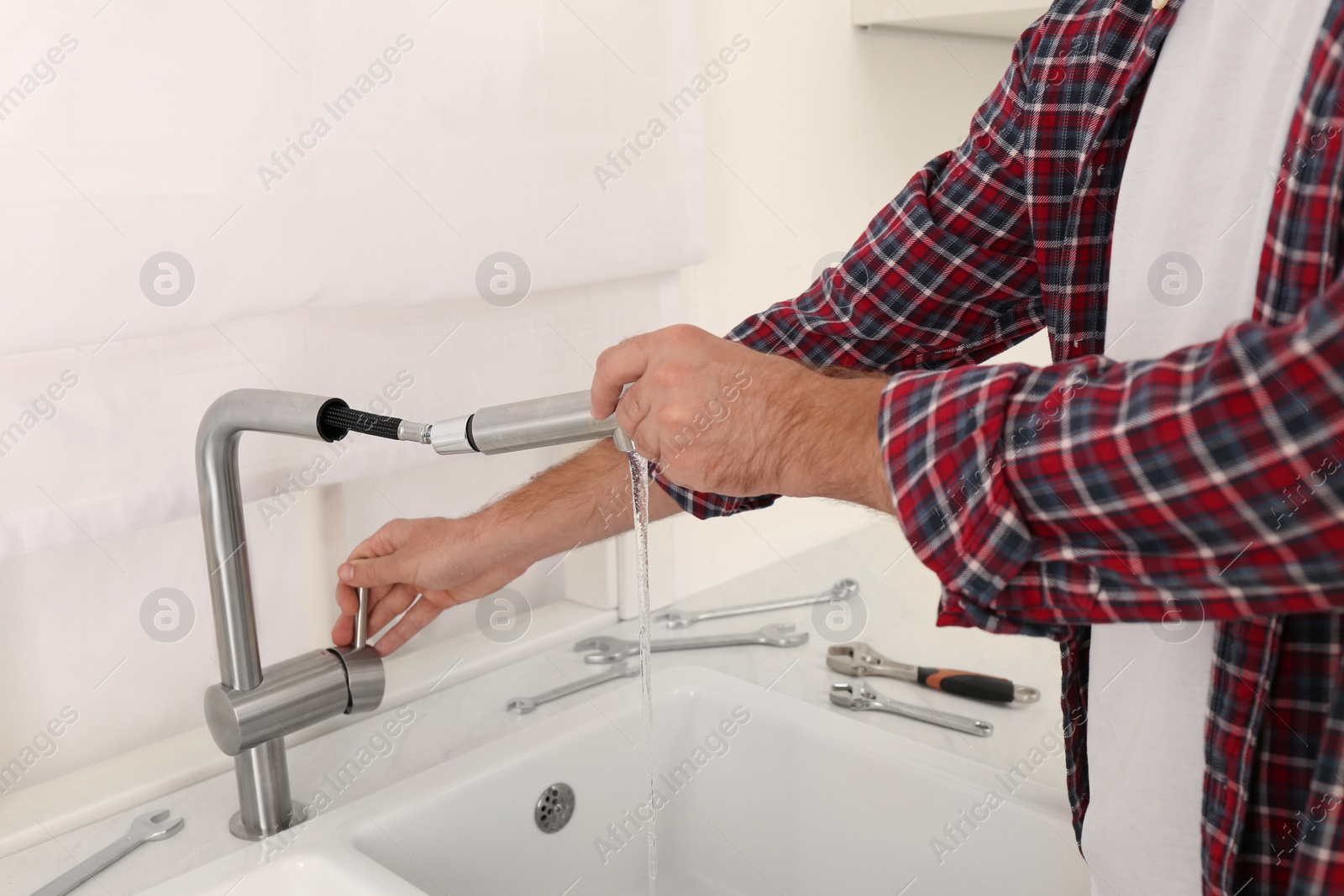 Photo of Man repairing water tap in kitchen, closeup