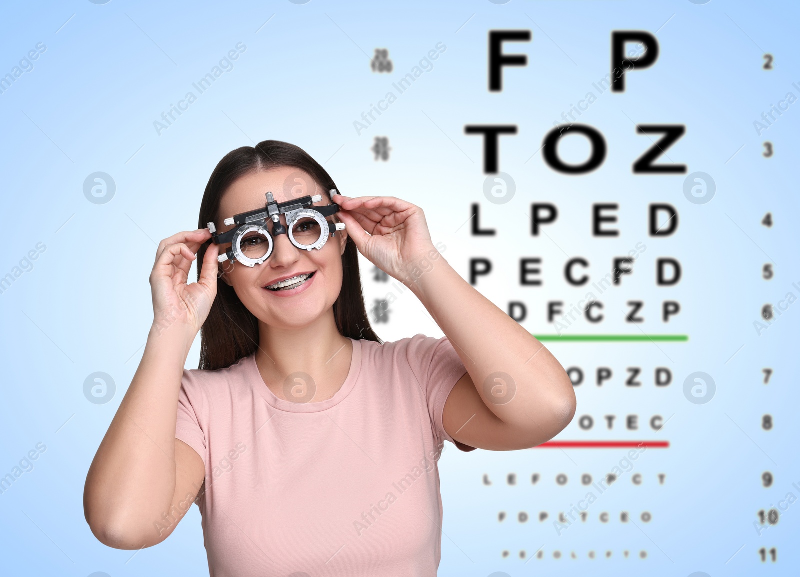 Image of Vision test. Young woman with trial frame and eye chart on gradient background