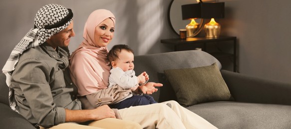 Image of Happy Muslim family with little son in living room, space for text. Banner design 