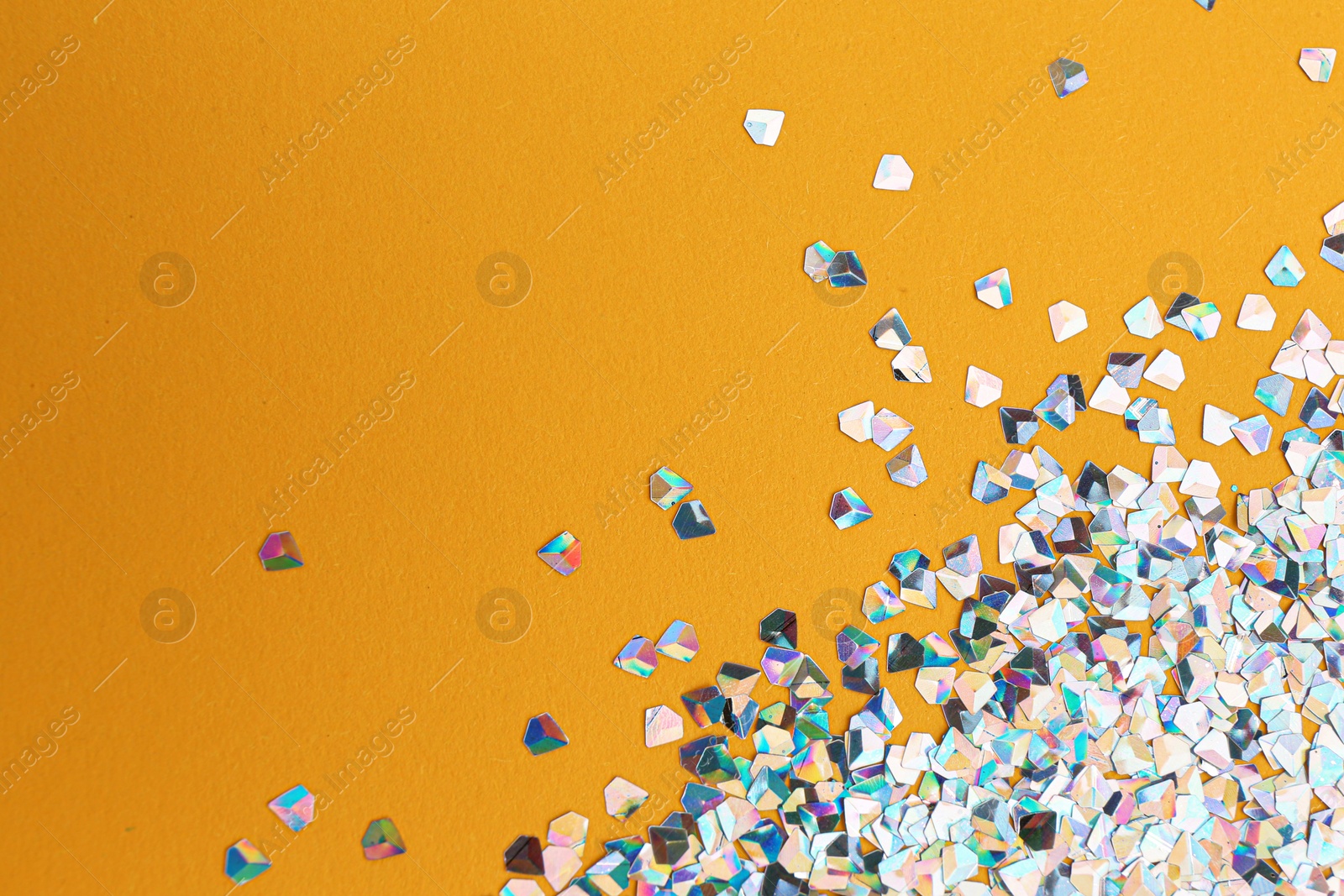 Photo of Shiny bright glitter on orange background. Space for text