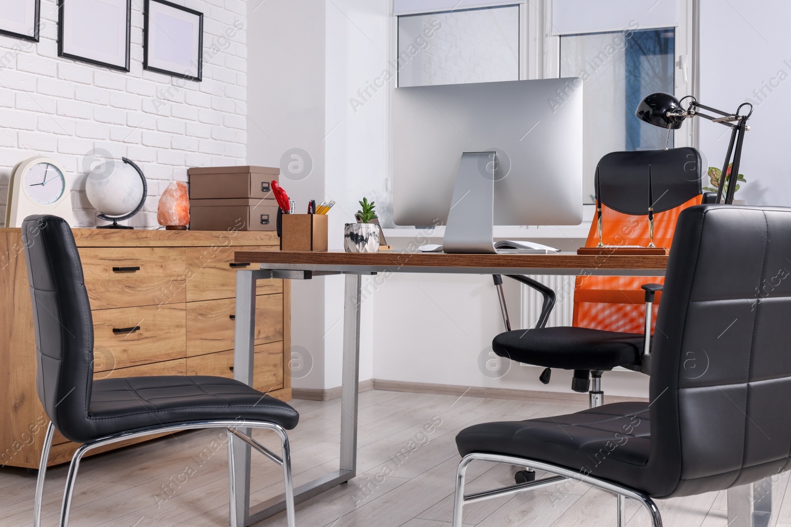 Photo of Stylish director's workplace with comfortable desk, computer and chairs for visitors in office. Interior design