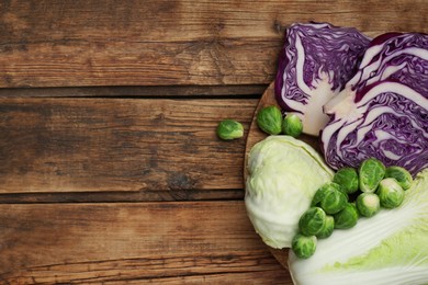 Different types of cabbage on wooden table, flat lay. Space for text