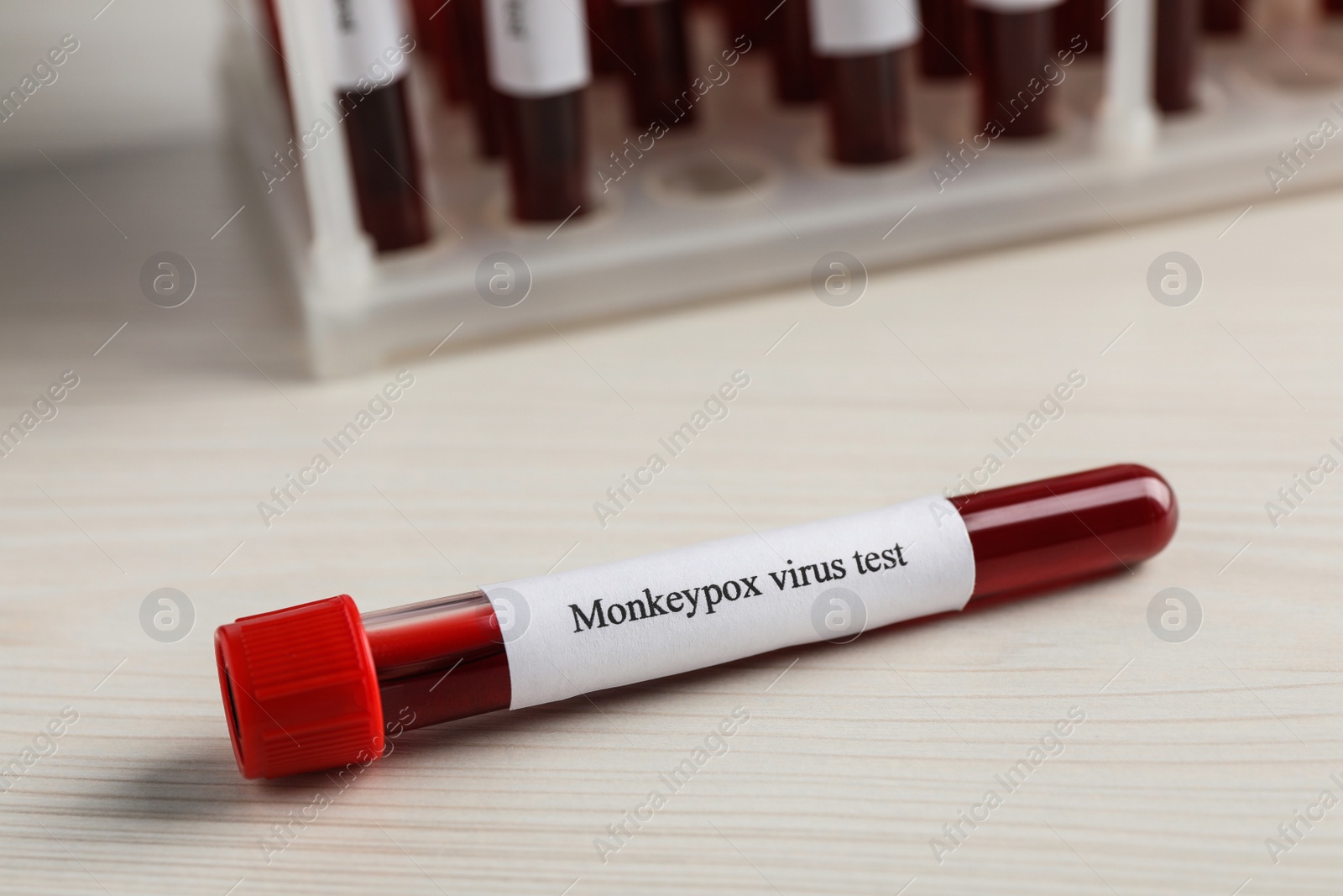 Photo of Monkeypox virus test. Sample tube with blood on wooden table