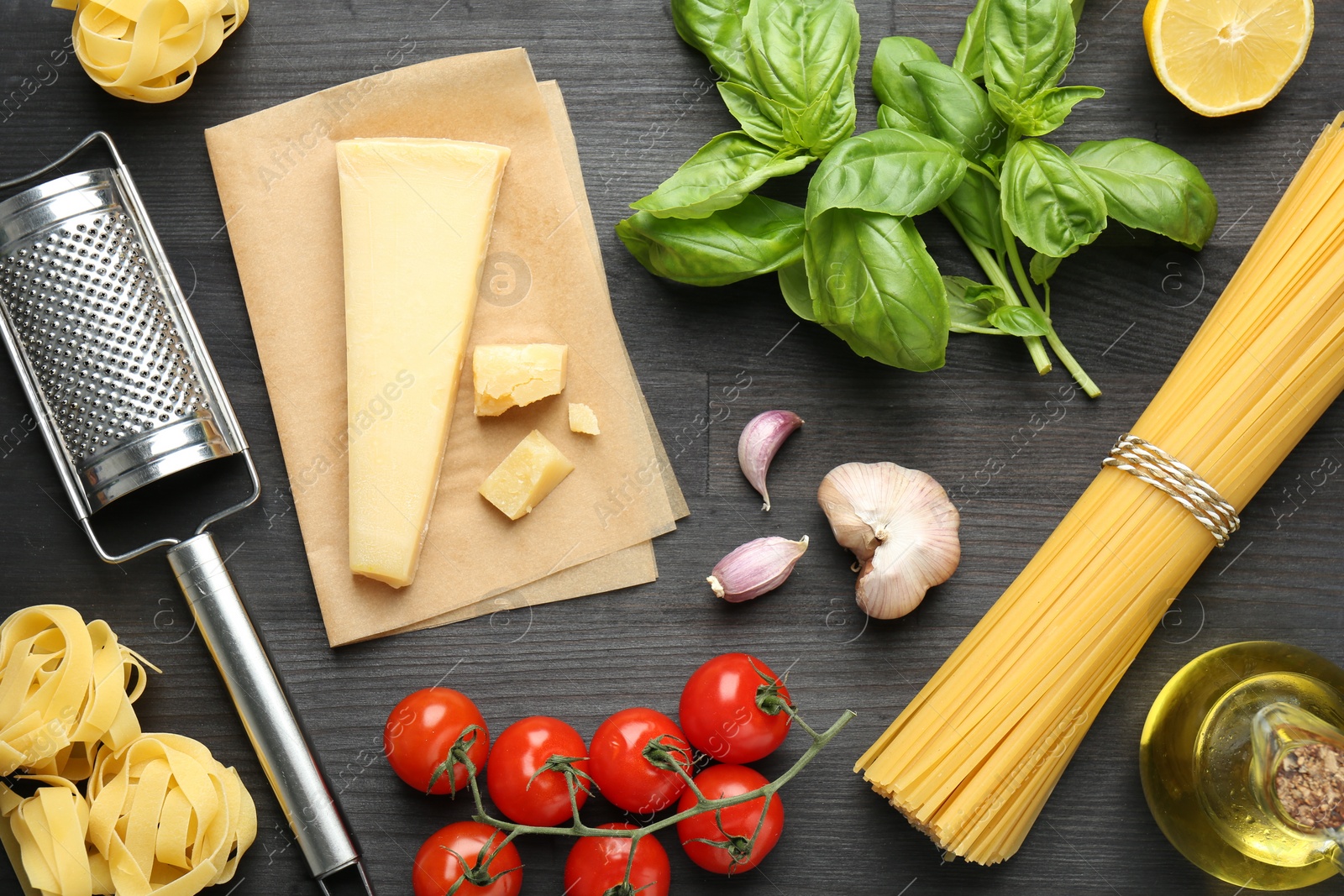 Photo of Different types of pasta, products and garter on dark wooden table, flat lay