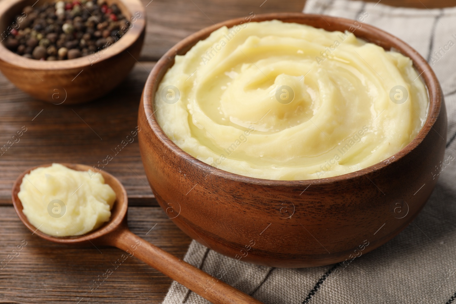 Photo of Bowl of tasty mashed potato and pepper on wooden table, closeup