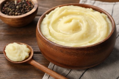 Bowl of tasty mashed potato and pepper on wooden table, closeup