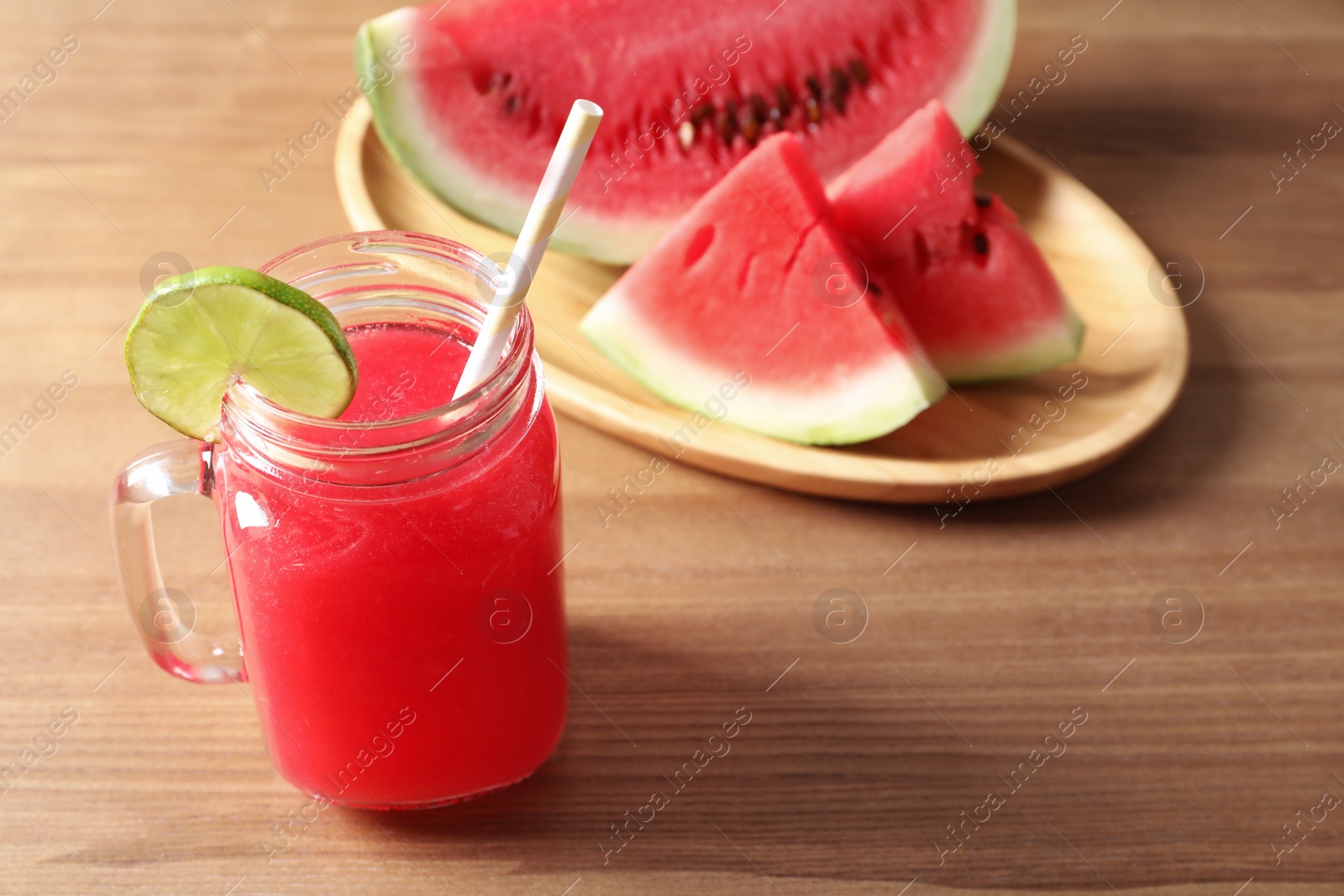 Photo of Summer watermelon drink in mason jar and sliced fruit on table