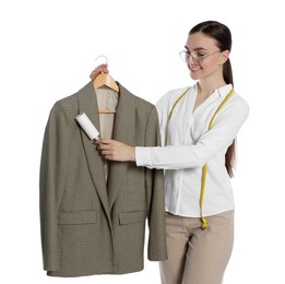 Young woman cleaning suit with lint roller on white background