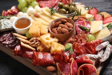 Photo of Assorted appetizers served on black wooden table, closeup