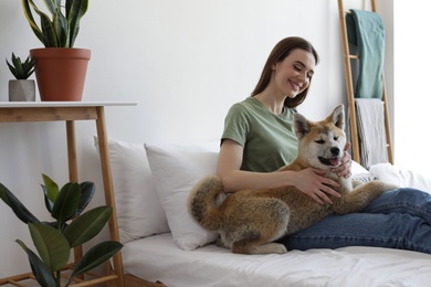 Young woman and Akita Inu dog in bedroom decorated with houseplants