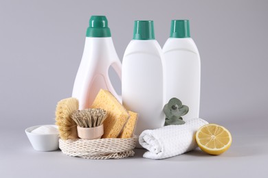 Bottles of cleaning product, sponges, brushes, lemon and baking soda on light background