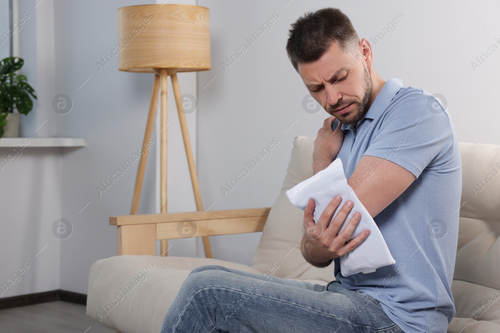 Photo of Man using heating pad at home, space for text