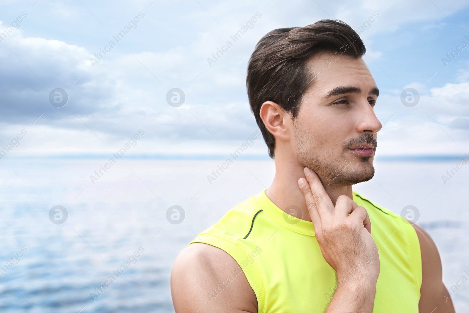 Photo of Young man checking pulse  after training on beach. Space for text