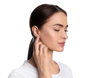 Young woman pointing at her ear on white background