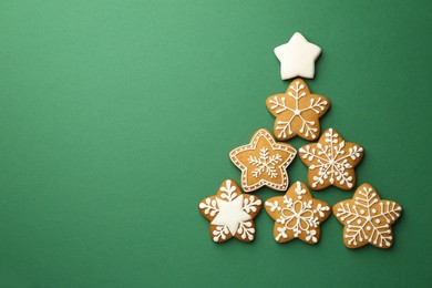 Photo of Christmas tree made of tasty cookies with icing on green background, flat lay. Space for text