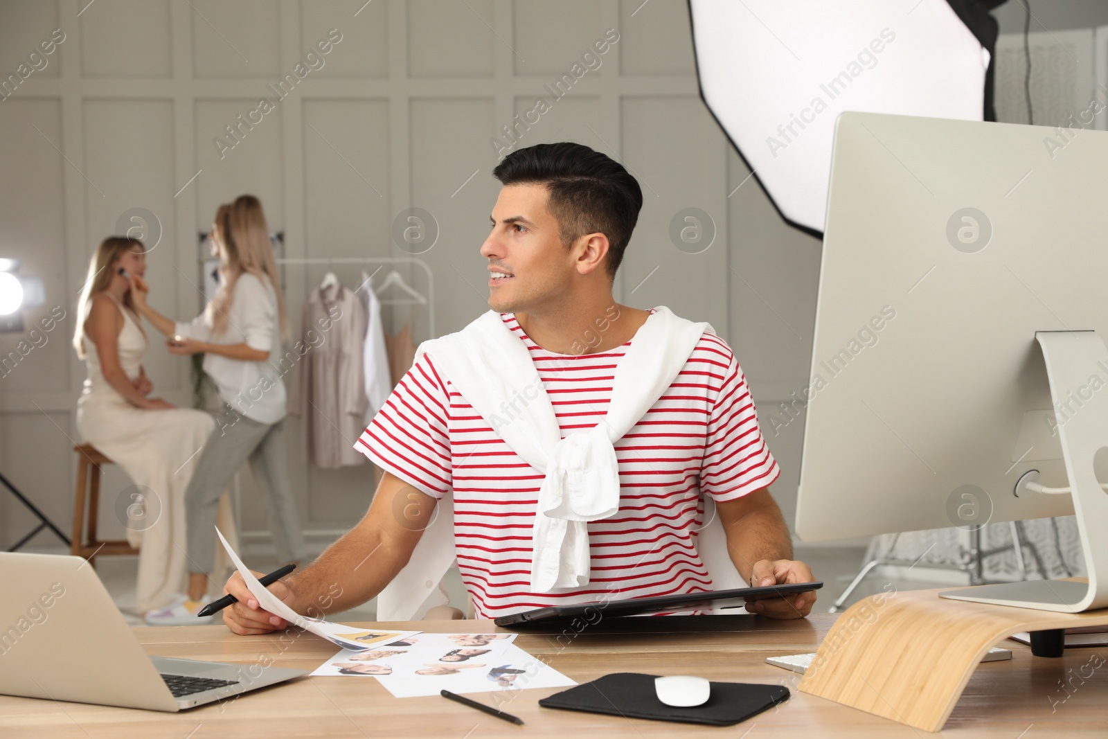 Photo of Professional retoucher working with graphic tablet at desk in photo studio