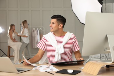 Photo of Professional retoucher working with graphic tablet at desk in photo studio