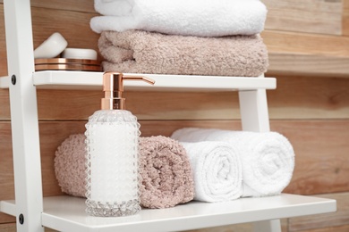 Photo of Towels and soap dispenser on shelf in bathroom