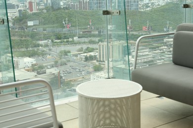 Photo of Coffee table and sofa against picturesque landscape of city in cafe