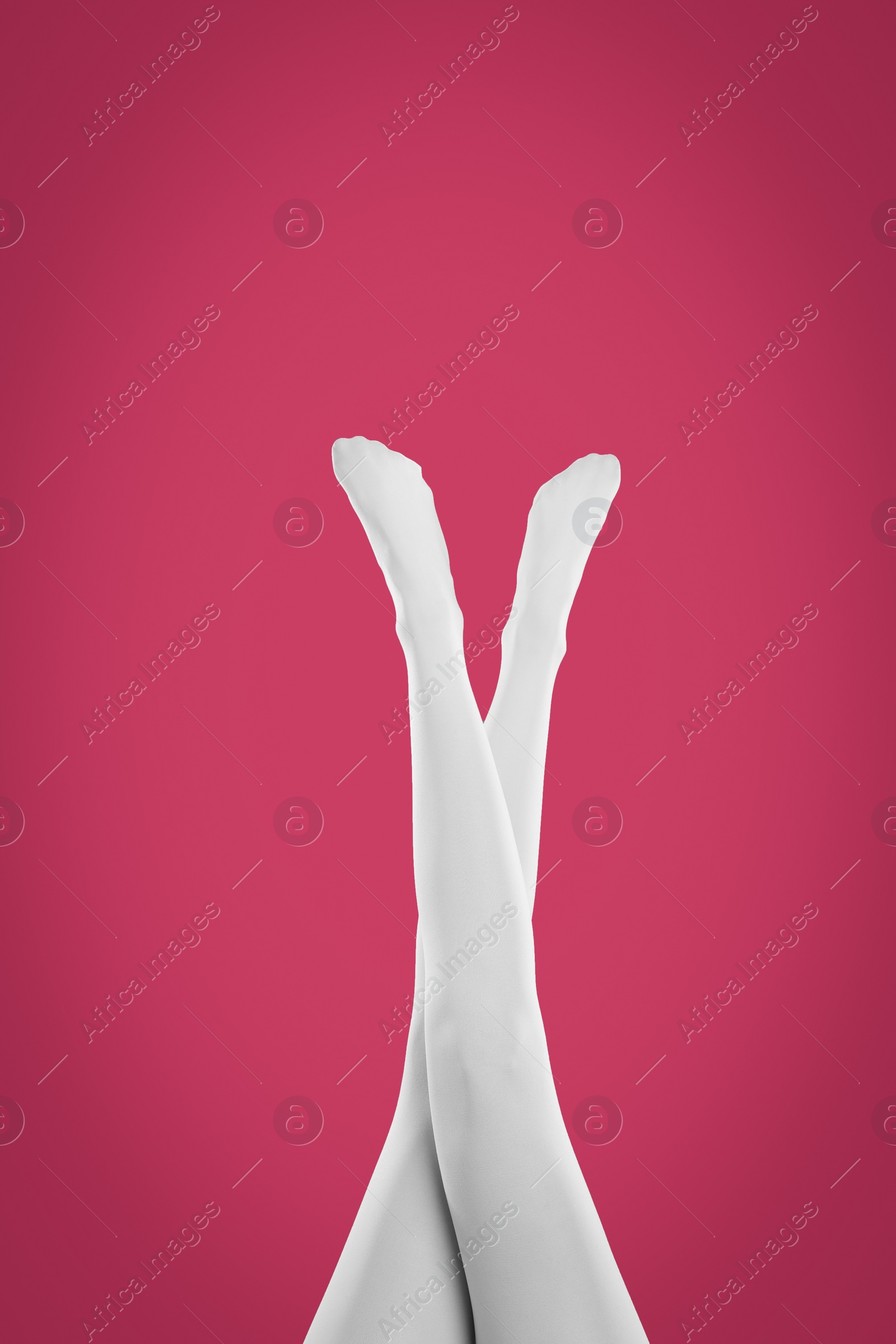 Photo of Woman wearing white tights on crimson background, closeup of legs