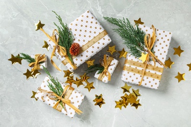 Photo of Christmas gift boxes with fir branches on light grey marble background, flat lay