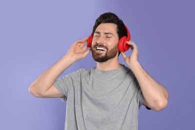 Photo of Happy man listening music with headphones on violet background