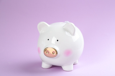 Photo of Cute white piggy bank on violet background