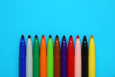 Photo of Many different colorful markers on light blue background, flat lay. Space for text