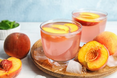 Photo of Tasty peach cocktail in glasses on table. Refreshing drink