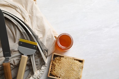 Photo of Different beekeeping tools and jar of honey on white table, flat lay. Space for text