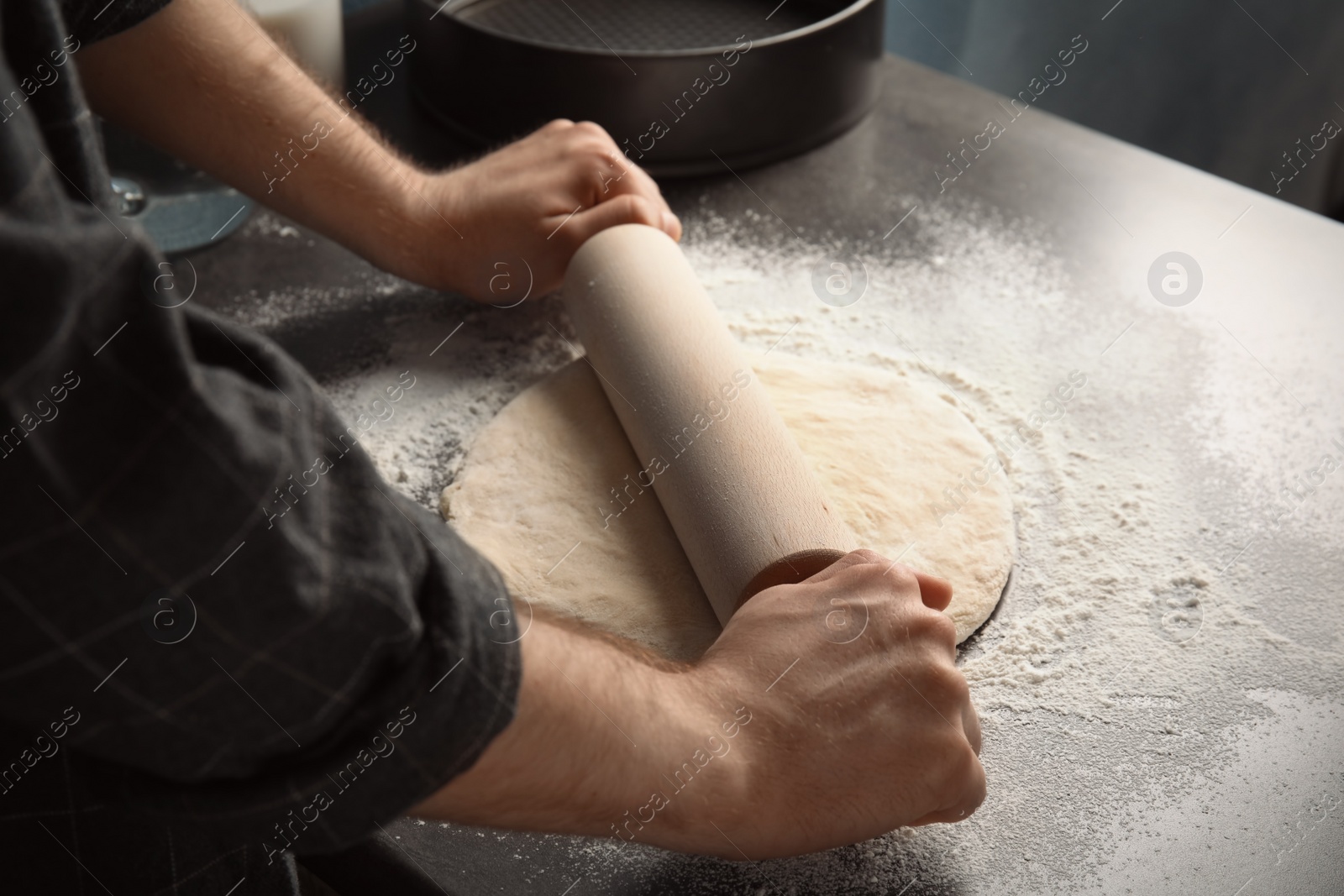 Photo of Man rolling dough for pizza on table