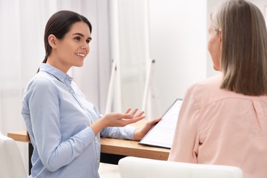 Photo of Notary consulting senior woman about Last Will and Testament in office, back view