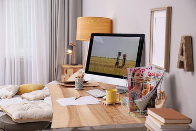 Comfortable workplace with modern computer near light wall in bedroom. Interior design