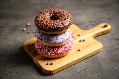 Photo of Sweet delicious glazed donuts on grey table