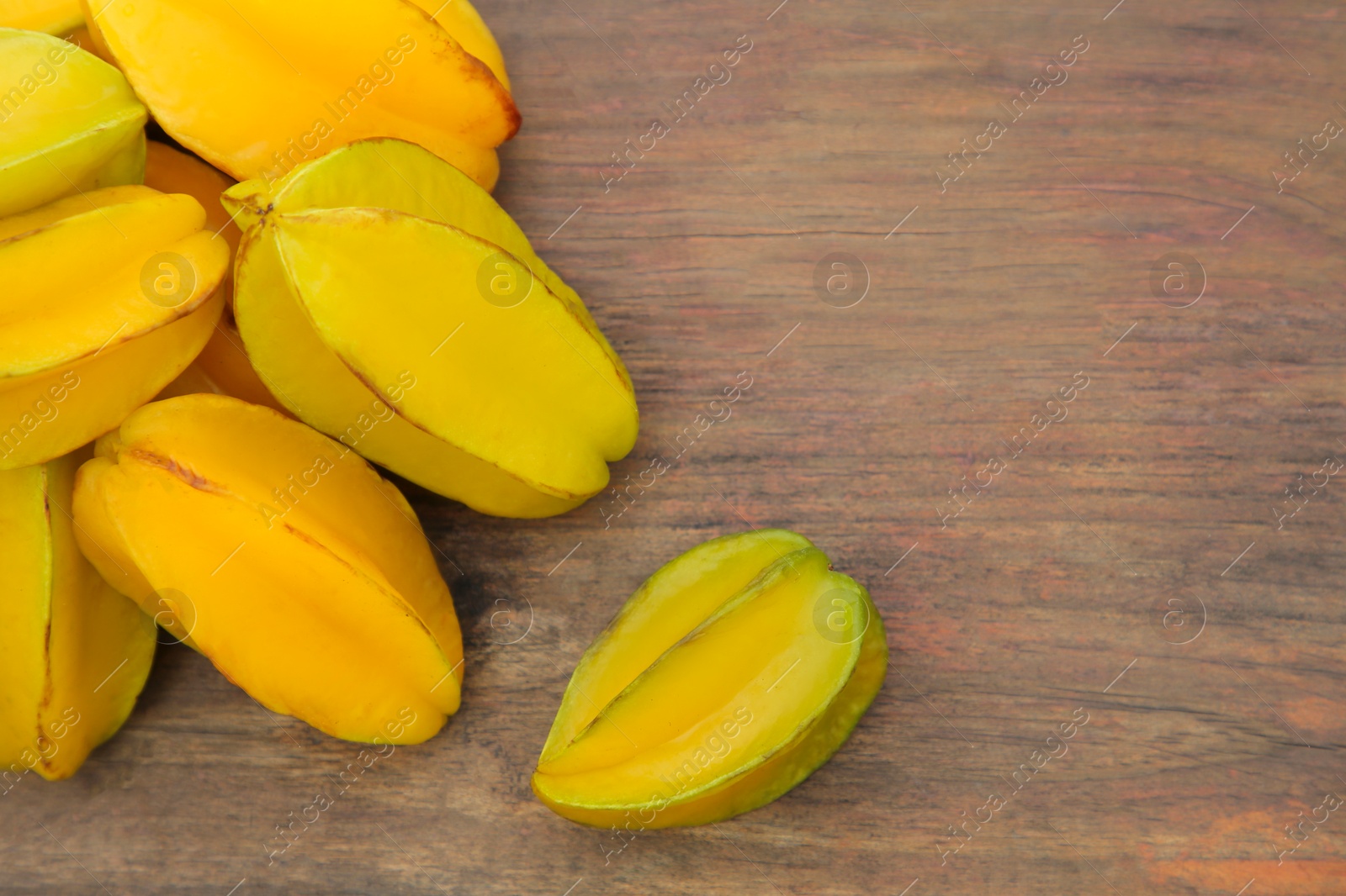 Photo of Delicious ripe carambolas on wooden table, flat lay. Space for text