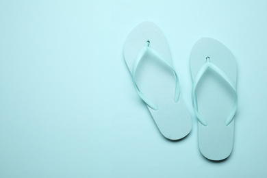 Photo of Pair of stylish flip flops on light blue background, top view with space for text. Beach objects