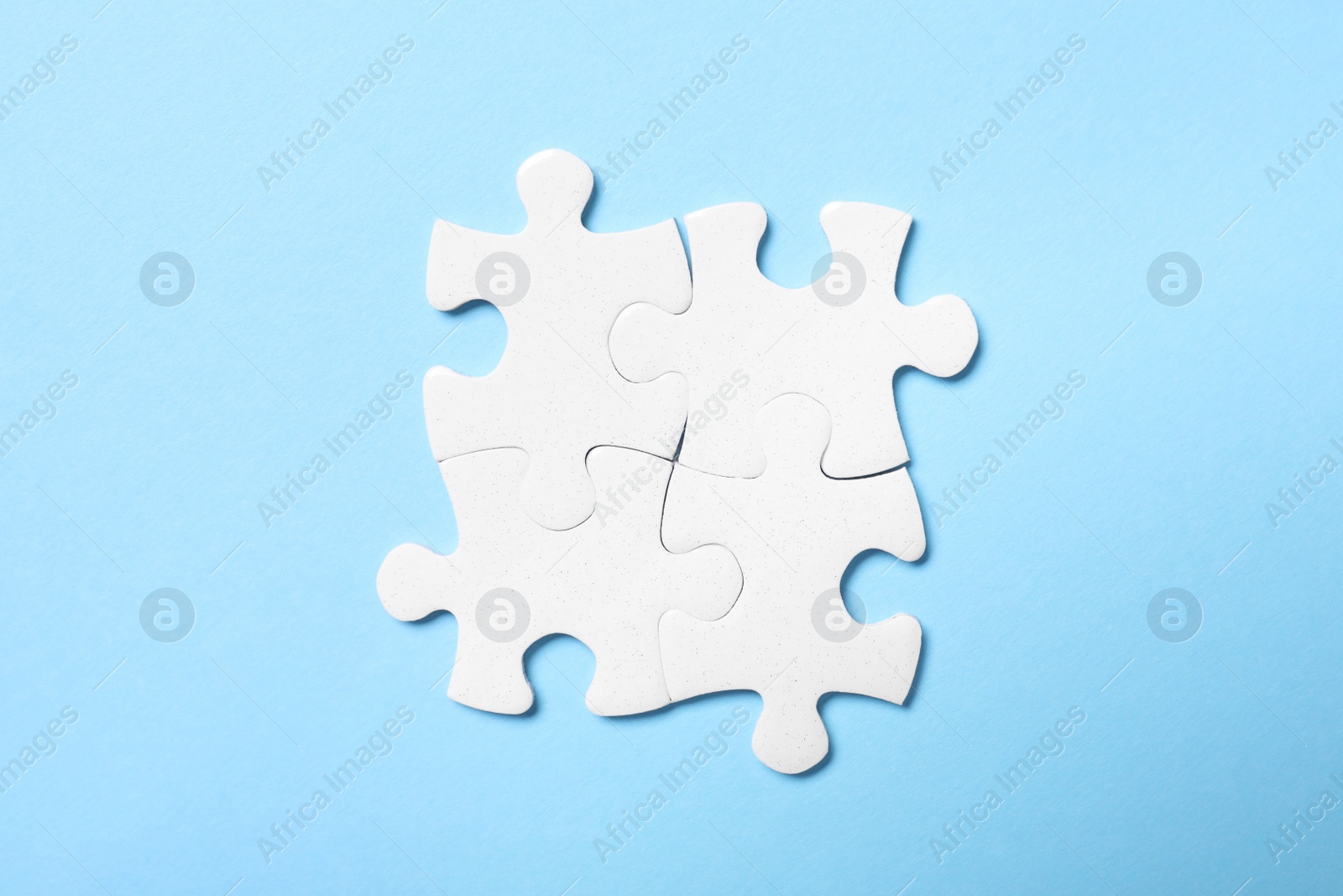 Photo of Blank white puzzle pieces on light blue background, flat lay