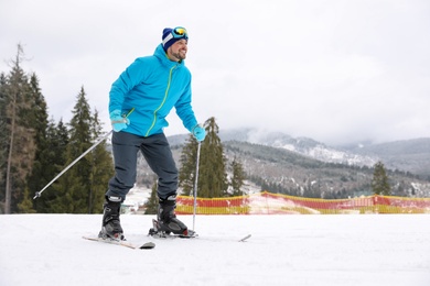 Male skier on slope at resort, space for text. Winter vacation