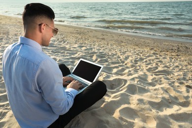 Businessman working with laptop on beach. Business trip